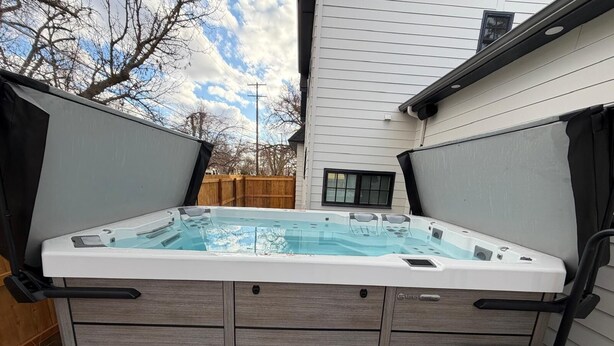 A hot tub with wooden steps and a wooden deck, surrounded by a wooden fence and a house. - Assemble Boise (Boise)