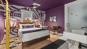 A modern bedroom with a bed, a desk, and a bathroom. - Assemble Boise (Boise)