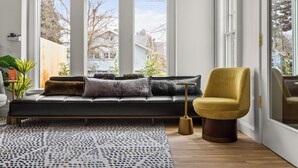 A modern living room with a black sofa, a yellow armchair, and a patterned rug. - Assemble Boise (Boise)