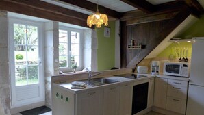 A kitchen with a central island, a sink, and a microwave. There is a window with a view of greenery outside. - Gabrielle's House (Giey-sur-Aujon)