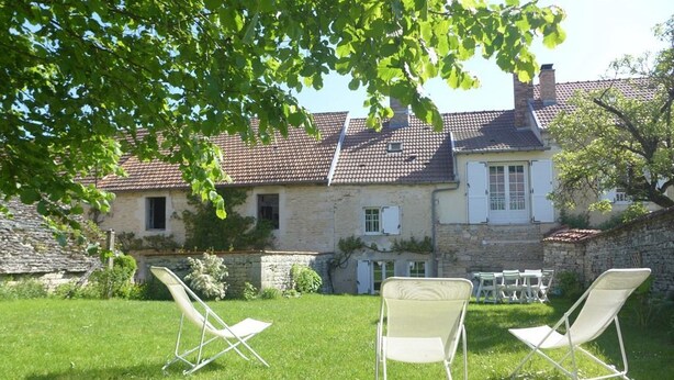 A stone house with a tiled roof, a grassy yard, and two white folding chairs. - Gabrielle's House (Giey-sur-Aujon)