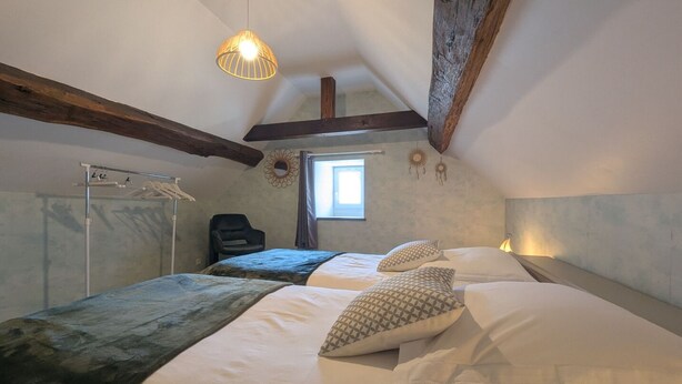 A bedroom with a large bed, a hanging light fixture, a window, and a wardrobe. - Simone de Beauvoir Guesthouse (Châteauvillain)