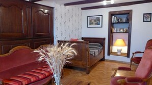 A room with a wooden sofa, a red armchair, a small table with a vase of dried plants, a wooden bed, and a bookshelf with a lamp. - MAISON ROSALICE - Chaumont-la-Ville (Chaumont-la-Ville)