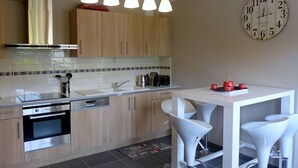 Una cucina moderna con mobili in legno, forno in acciaio inossidabile, lavello e tavolo da pranzo bianco con sgabelli da bar.