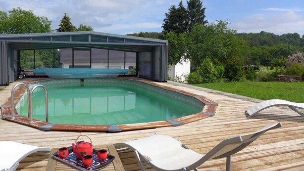 Una piscina con lettini e un tavolo con teiere, circondata da un pontile in legno e un'area coperta.