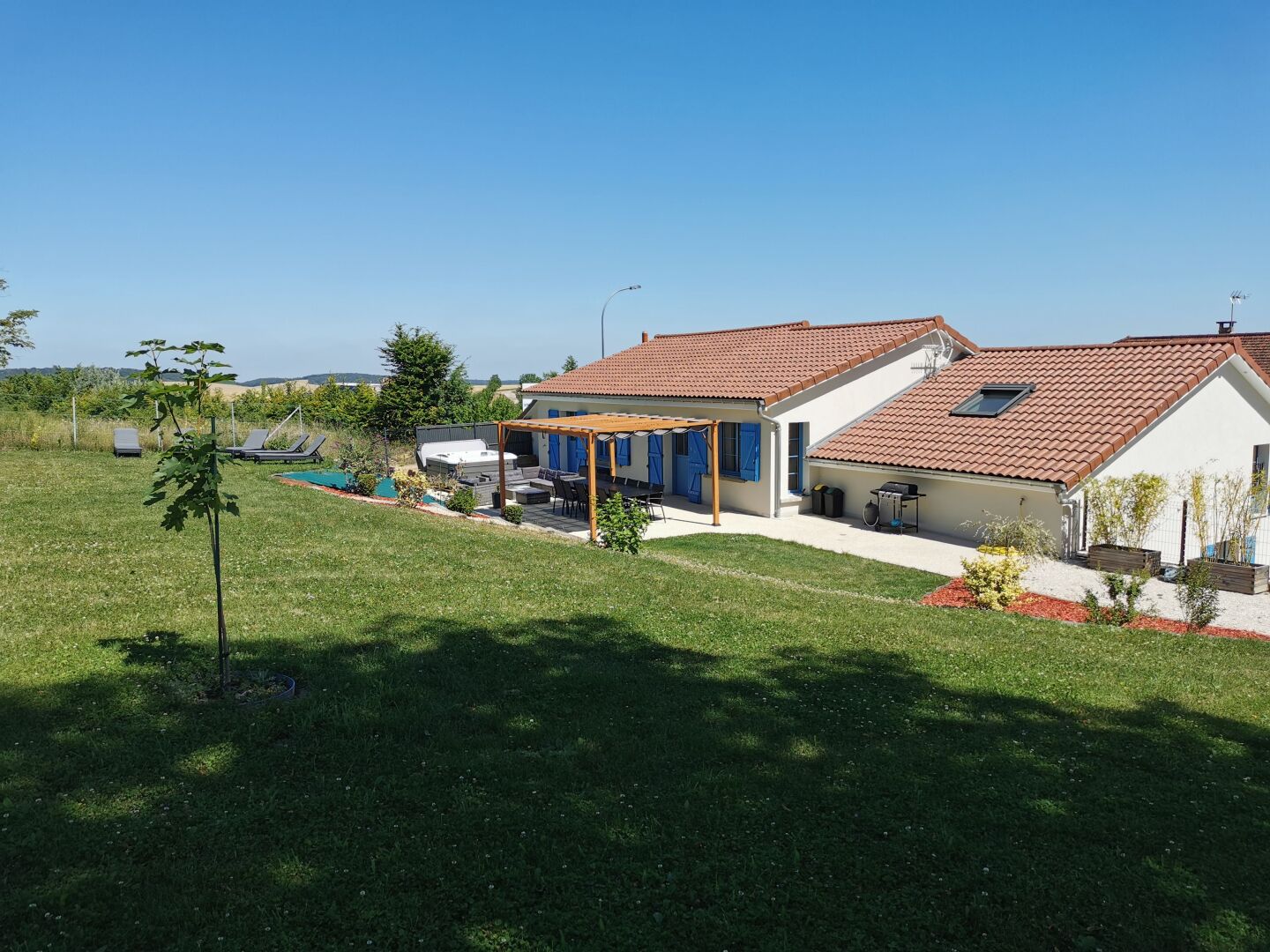Ein Haus mit einer Terrasse, einem Schwimmbad und einem Garten.