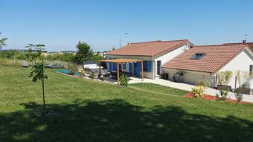Ein Haus mit einer Terrasse, einem Schwimmbad und einem Garten.