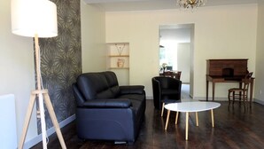 A living room with a dark leather sofa, a round white table, and a wooden cabinet. - Graine - Dommartin-le-Franc (Dommartin-le-Franc)