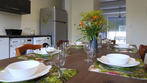 A dining area with a table set for four, a refrigerator, a washing machine, and a vase with flowers. - Graine - Dommartin-le-Franc (Dommartin-le-Franc)
