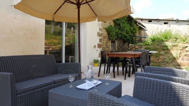An outdoor patio with wicker furniture, a table, and an umbrella. - Graine - Dommartin-le-Franc (Dommartin-le-Franc)