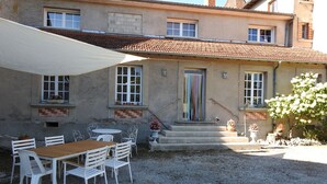 A building with a tiled roof, a covered patio with a table and chairs, and a staircase leading to the entrance. - Gîte de la Forge - ROCHES-BETTAINCOURT (ROCHES-SUR-ROGNON)