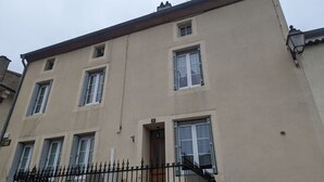 A multi-story building with a beige facade, multiple windows, and a black metal fence in the foreground. - Stopover at Côna - Bourmont (Bourmont)