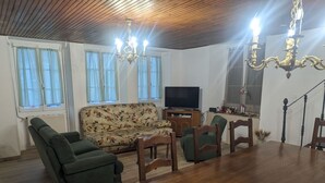 A living room with a wooden ceiling, a sofa, a TV, and a dining table with chairs. - Stopover at Côna - Bourmont (Bourmont)