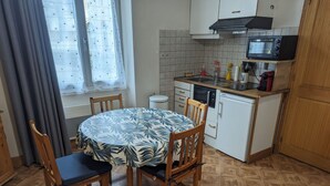 Cocina compacta con zona de comedor. Incluye una mesa redonda con sillas, microondas, fregadero y lavavajillas.
