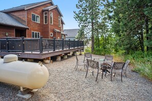 A wooden house with a deck, outdoor seating, and a large white object on the ground.