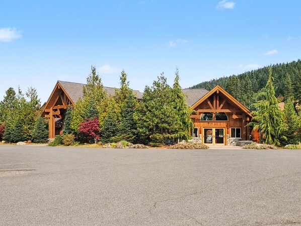 A lodge with a large parking lot, wooden cabins, and a forested backdrop.