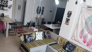 A living room with a sofa, a dining table, and a hanging chair.