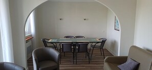A dining area with a table and chairs, an arched doorway, and a sofa.