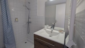 Un baño moderno con ducha, inodoro y tocador con espejo.