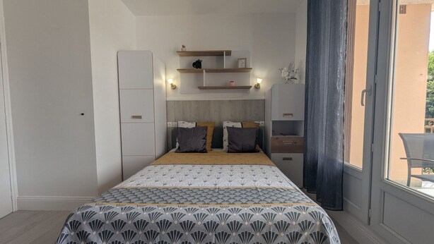 Un dormitorio con cama, mesitas de noche, un armario y ventana con vistas.