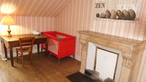 Une pièce chaleureuse avec une table en bois, une chaise rouge, une lampe et une cheminée.