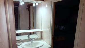 Une salle de bain avec un lavabo blanc, un miroir et un meuble.