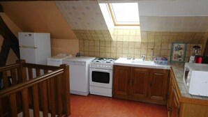 Une cuisine compacte dotée d’un puits de lumière, de meubles en bois, d’une cuisinière, d’un lave-vaisselle et d’un four à micro-ondes.