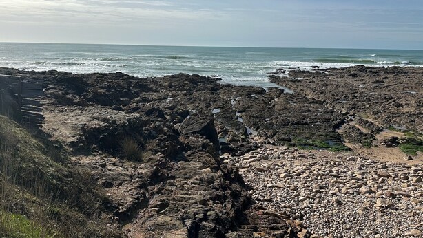 Paesaggio costiero roccioso con vista limpida sull'oceano.