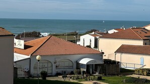 Una zona residenziale sulla costa con case a tetti in terracotta e una vista libera sul mare, con un cartello che indica il ristorante 'La Folie'.
