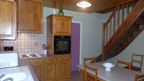 Een keuken met houten kastjes, een fornuis en een eettafel met stoelen.
