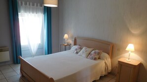 Una camera da letto con un letto, due comodini con lampade, una finestra con tende e un termosifone.