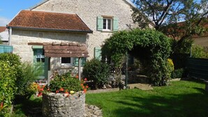 Una casa in pietra con tetto spiovente e persiane verdi.