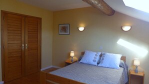 A bedroom with a wooden bed, two bedside tables with lamps, a wooden wardrobe, and a skylight. - The White Stones (Aubepierre-sur-Aube)