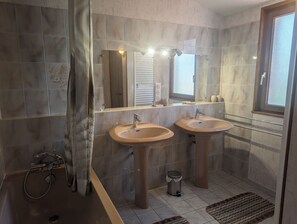 Ein Badezimmer mit zwei Waschbecken, einer Dusche und einem Fenster.