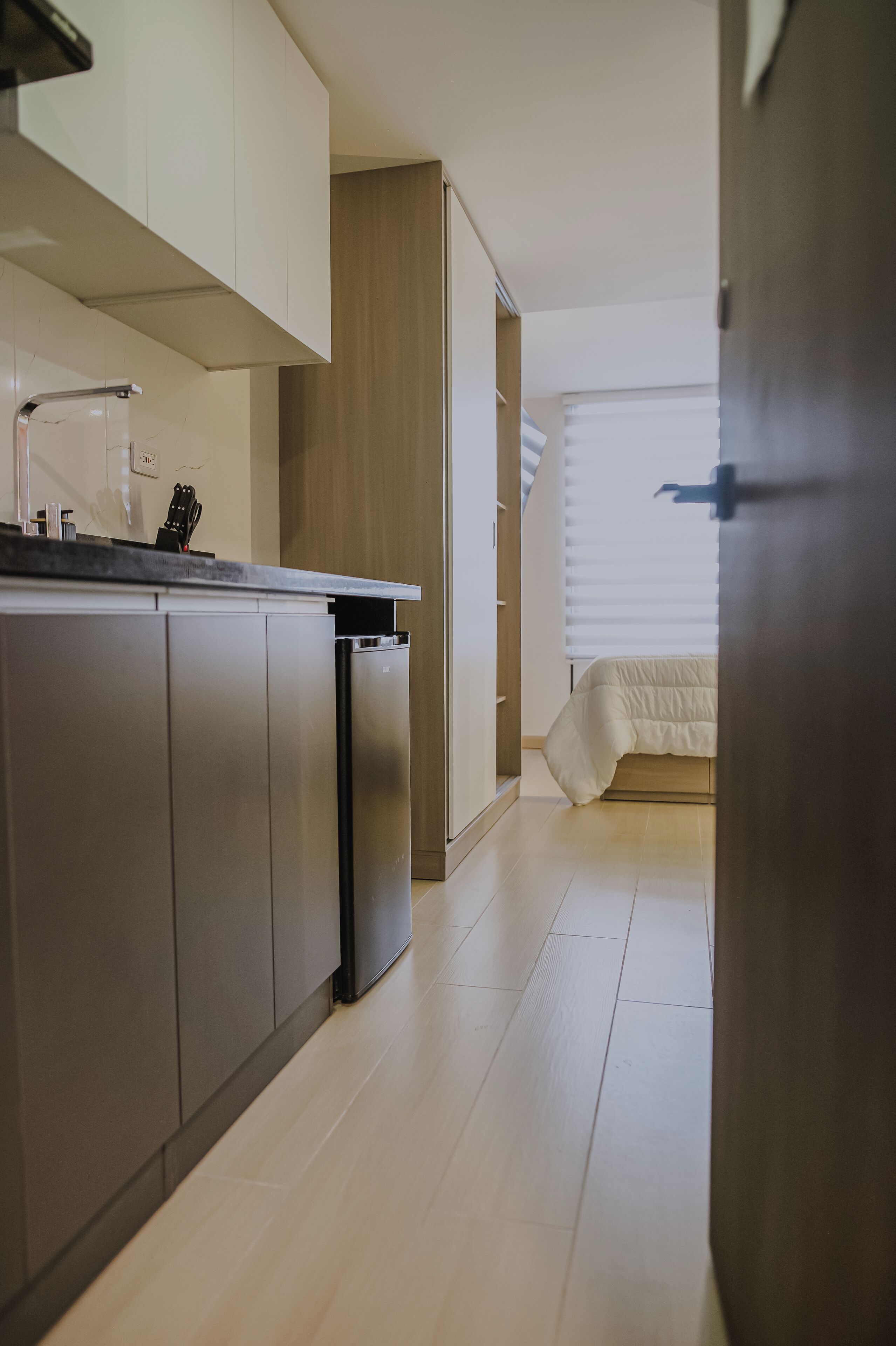 Una cocina moderna con electrodomésticos integrados, un comedor y un dormitorio con cama y ventana.