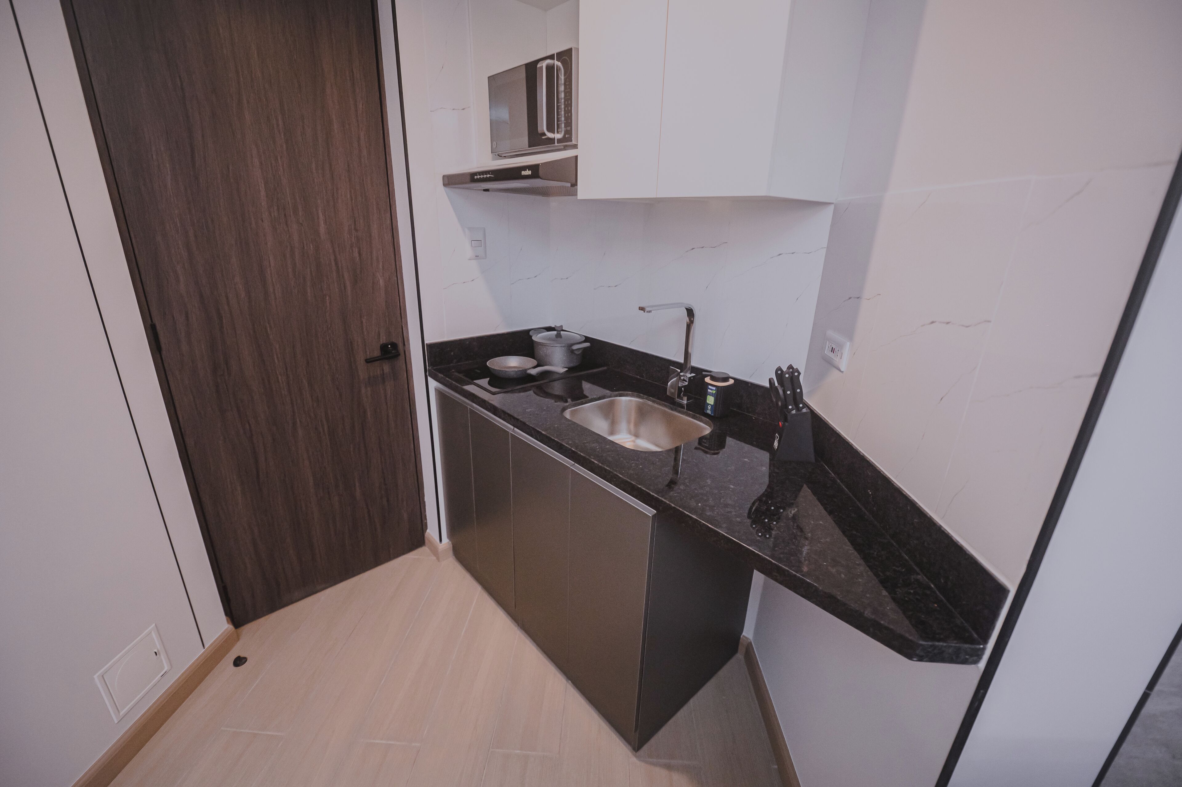 A compact kitchen with a sink, countertop, and cabinets.