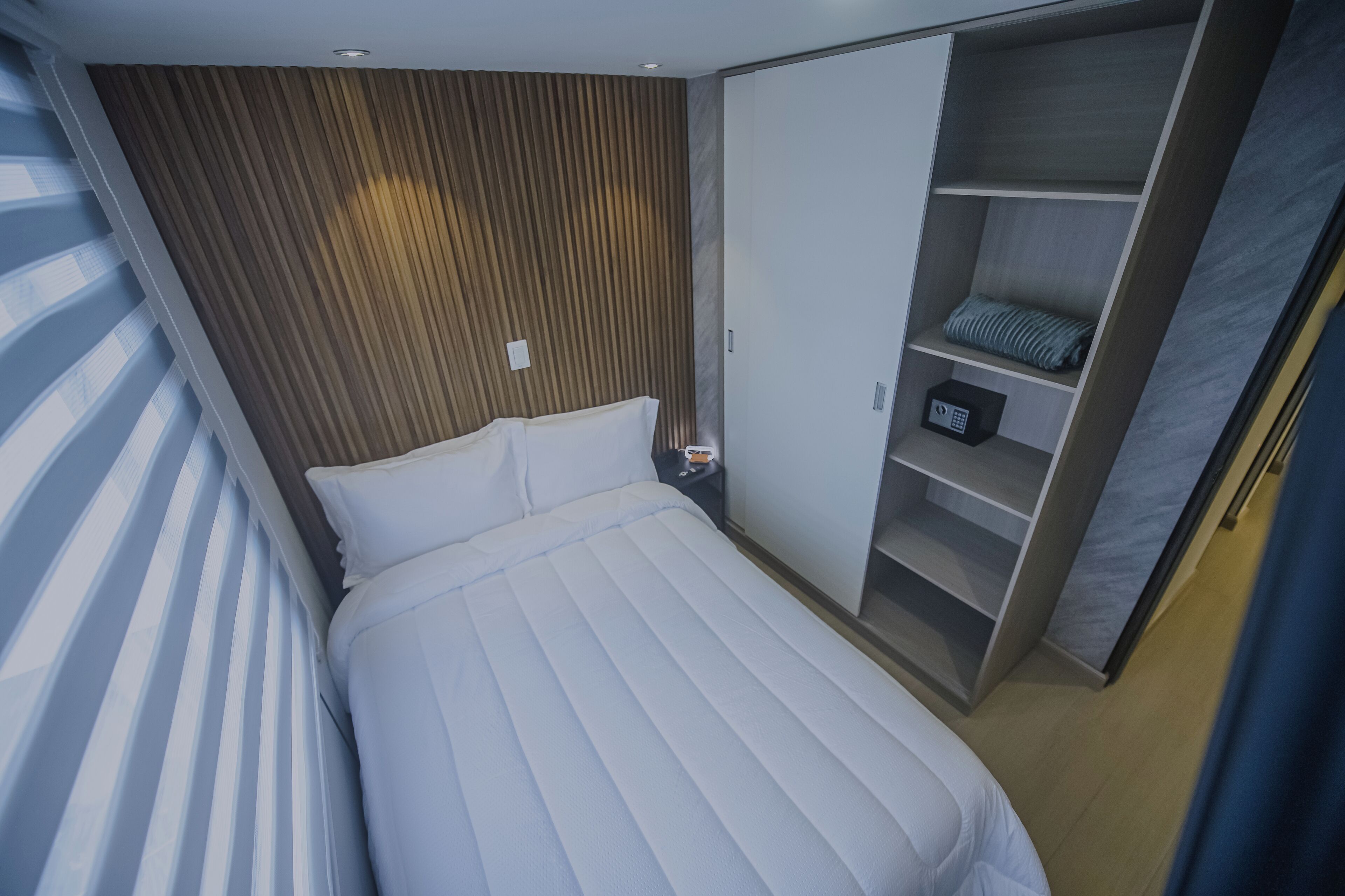 Quarto com cama, guarda-roupa e mesa de cabeceira.