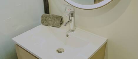 A bathroom with a white sink, a round mirror, and a towel on the counter.