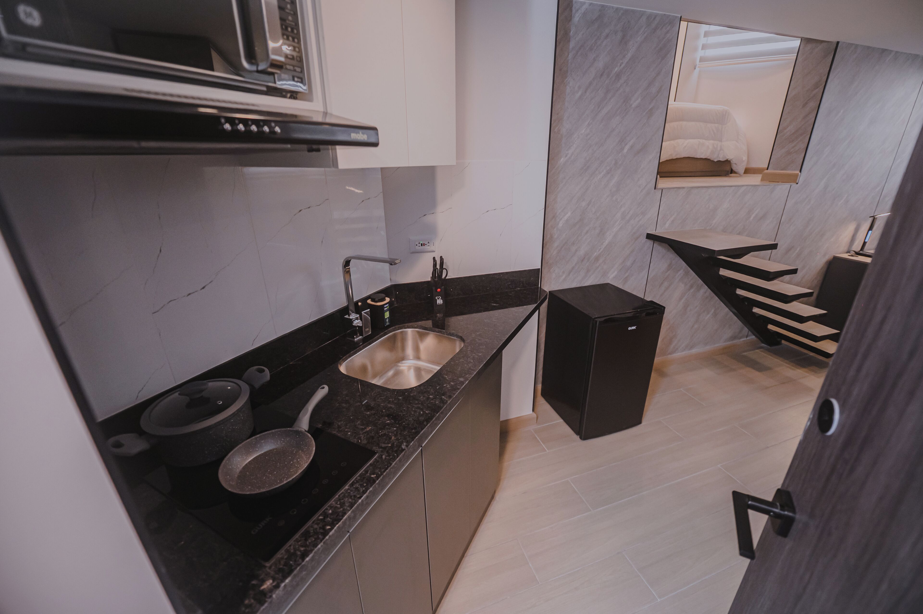 A modern kitchen with a built-in stove, a sink, and a compact refrigerator.