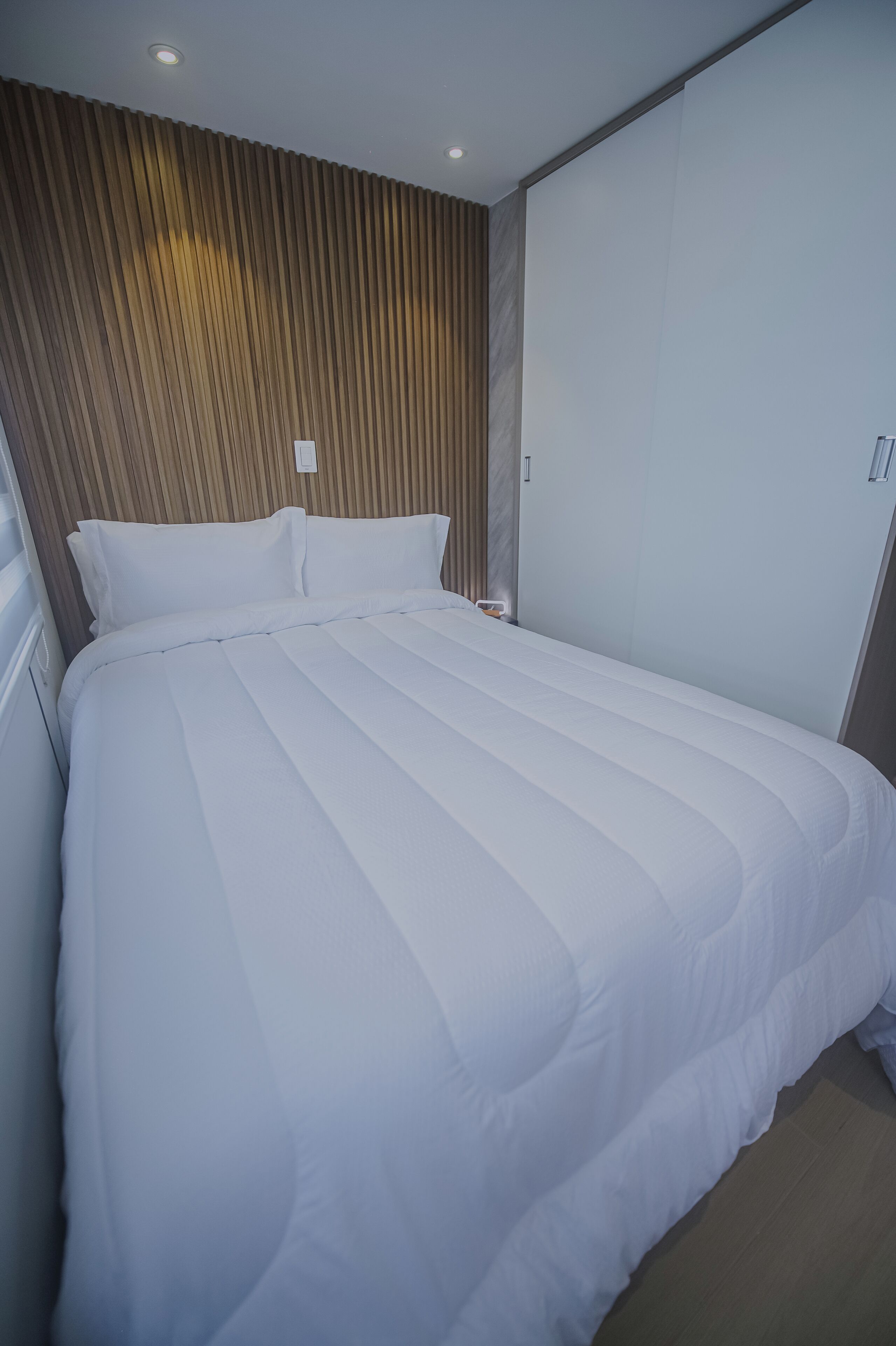 Uma cama grande com roupa de cama branca num quarto de hotel.