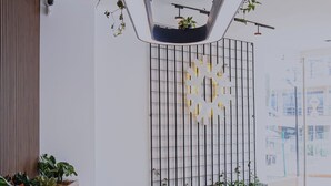 A modern interior with a seating area, two round tables, a decorative light fixture, and a plant wall. - Torre U Kooliving (Manizales)