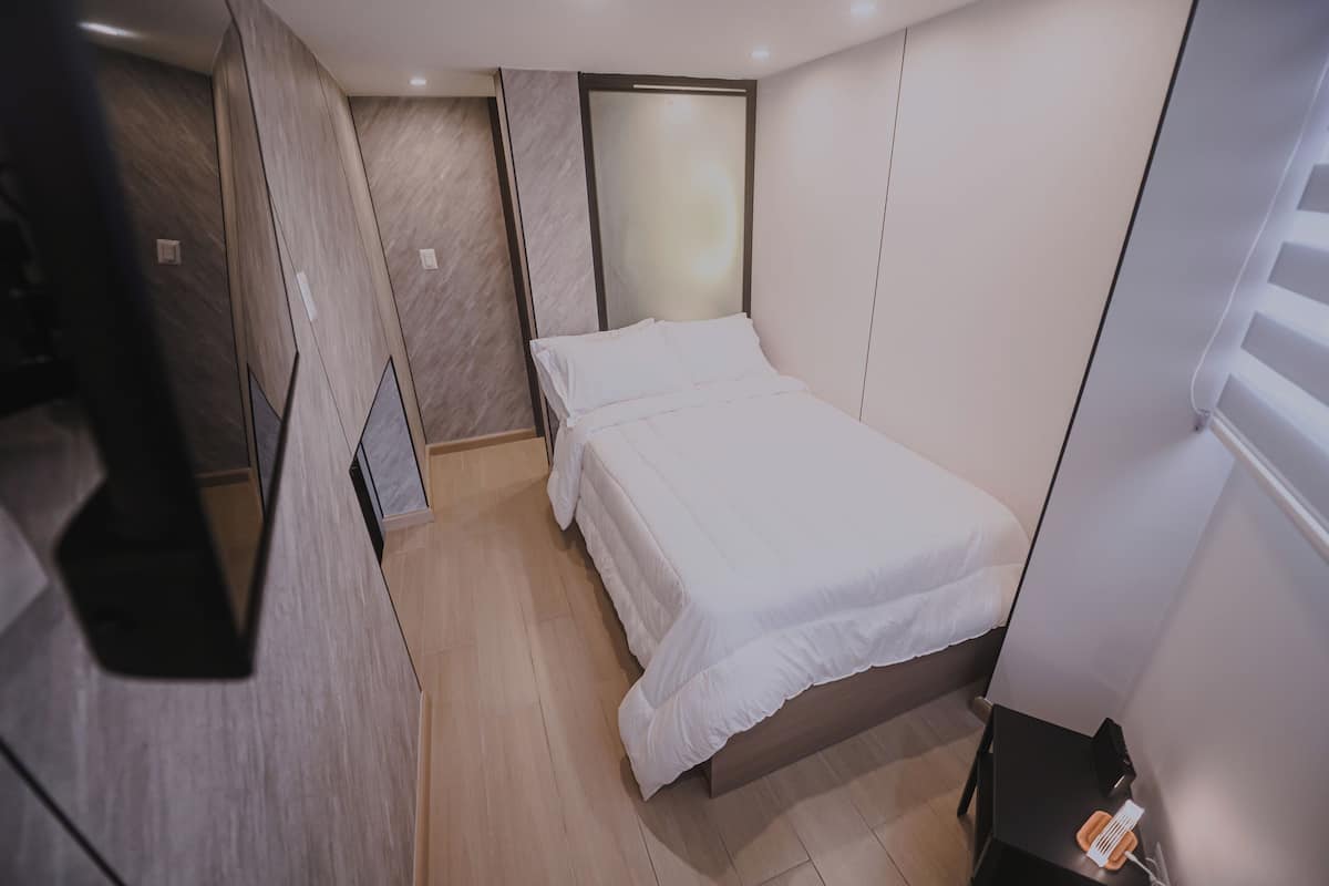 Une petite chambre à coucher moderne, avec un lit simple, une table de chevet et une armoire.