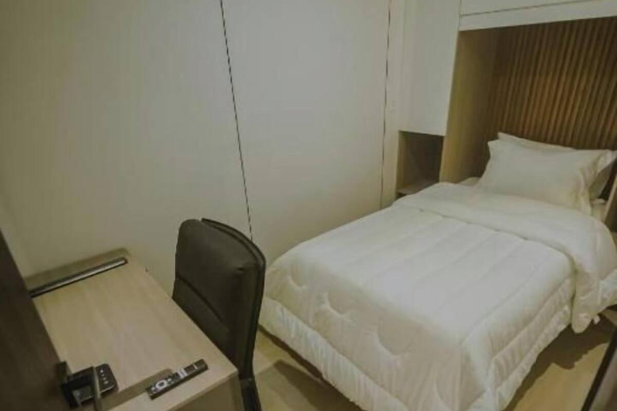 Une petite chambre à coucher, bien rangée, avec un lit, un bureau et une chaise.