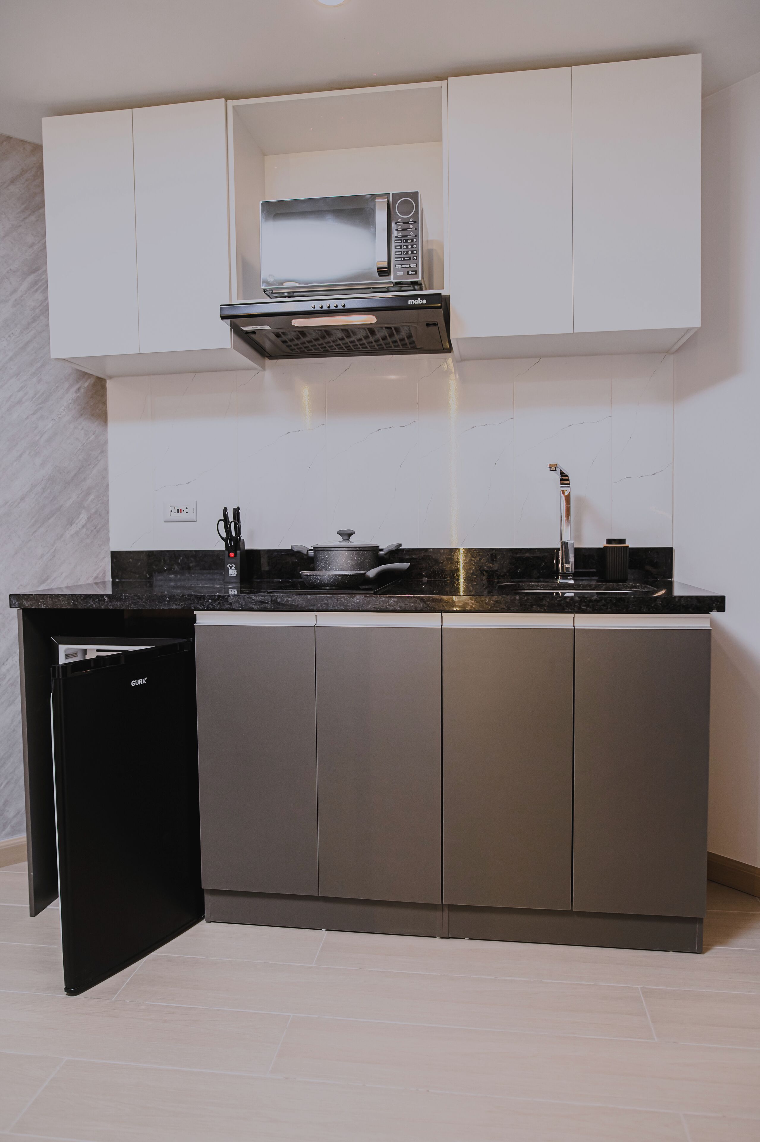 A compact kitchen with a built-in microwave, a stovetop, and a dishwasher.