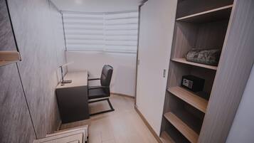 Une chambre à coucher de taille réduite, équipée d’un bureau, d’une chaise et d’une armoire intégrée.