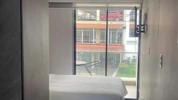 Ein Schlafzimmer mit einem Bett, einer Schiebetür, die auf einen Balkon führt, und einer Deckenleuchte.