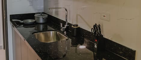 Een moderne keuken met witte kasten, een zwart aanrecht, een roestvrijstalen spoelbak en een vaatwasser.