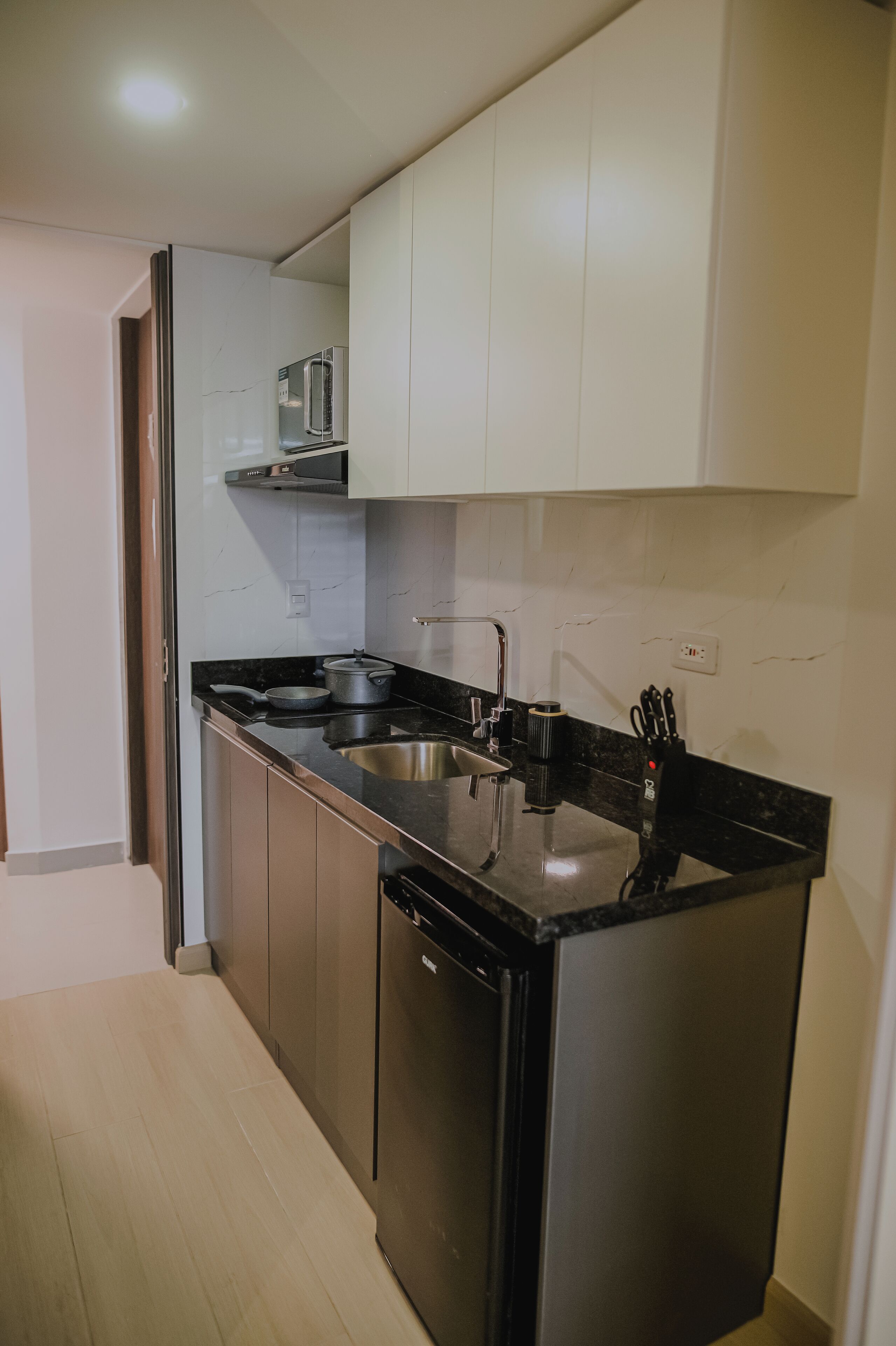 A modern kitchen with a stainless steel refrigerator, a double sink, and a microwave above the counter.