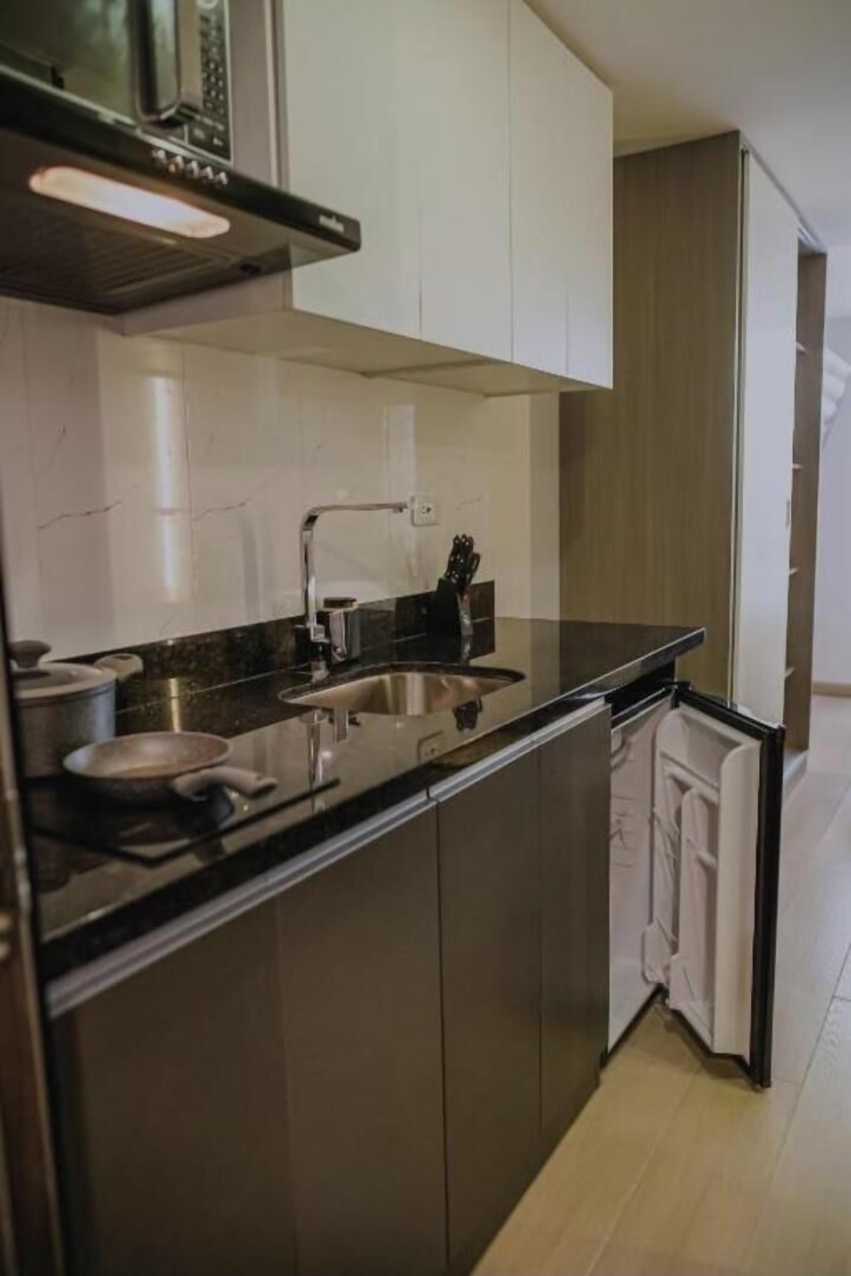 Ett modernt kök med en diskho i rostfritt stål, en mikrovågsugn och skåp.