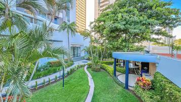 A modern building with a well-maintained garden, a pathway, and a blue structure.